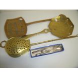 Two silver hallmarked handled pickle forks, a plated sugar spoon, a copper chestnut roaster and