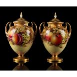 A pair of Royal Worcester two-handled vases & covers, each painted with fruit by J Smith, both