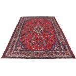 A Hamadan woollen hand-made carpet with red ground, 121 by 84ins. (307 by 213cms.)(see