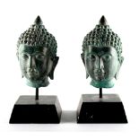 Property of a lady - a pair of bronze Buddha heads, on plaster filled wooden bases, each 2.75ins. (