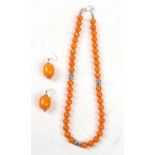 An Indian amber type necklace with white metal mask beads; together with a matching pair of earrings
