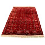 A Turkoman woollen hand-made rug with red ground, 114 by 78ins. (289 by 197cms.) (see