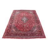 A Meshed woollen hand-made carpet with red ground, 155 by 117ins. (393 by 296cms.) (see