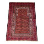 A Belouch rug with red ground, 55 by 33ins. (138 by 84cms.) (see illustration).