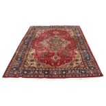 A Tabriz woolllen hand-made carpet with dark red ground, 122 by 82ins. (310 by 207cms.) (see