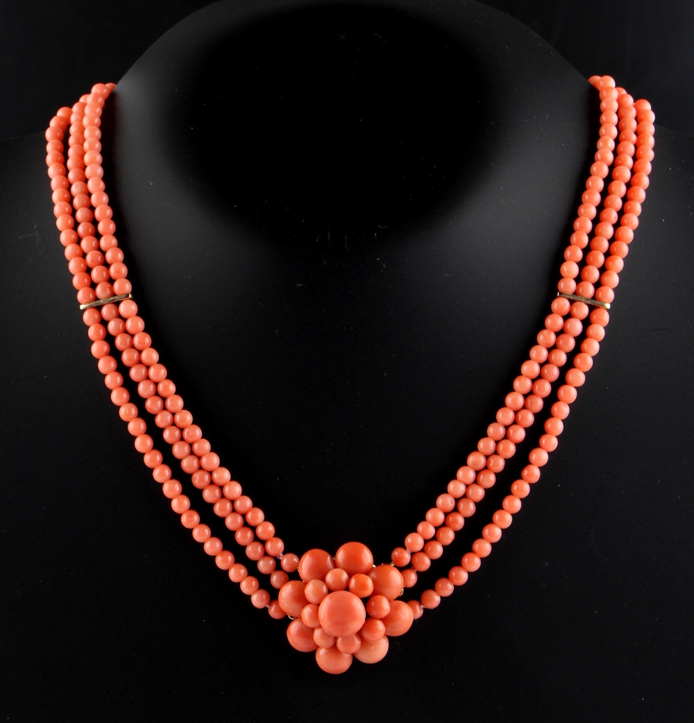 A coral three row necklace with flowerhead centre, the beads approximately 4.4mm diameter, the