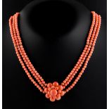 A coral three row necklace with flowerhead centre, the beads approximately 4.4mm diameter, the