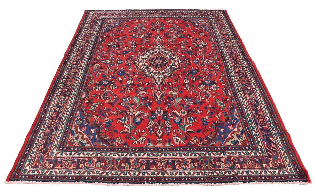 A Hamadan woollen hand-made carpet with red ground, 121 by 84ins. (307 by 213cms.)(see