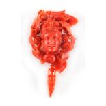 A carved coral brooch modelled as a Bacchanalian mask framed by fruit, flowers & leaves, with