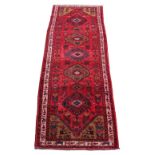 A Hamadan woollen hand-made runner with red ground, 116 by 39ins. (295 by 100cms.) (see