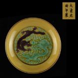 A Chinese yellow ground porcelain shallow dish with incised decoration depicting a green dragon & an