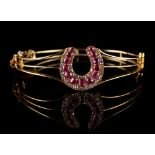An 18ct yellow gold ruby & diamond hinged bracelet, of openwork design with horseshoe shaped panel