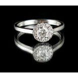 An 18ct white gold diamond cluster ring, the central modern round brilliant cut diamond weighing