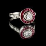 A platinum or white gold ruby & diamond target cluster ring, the centre millegrain collet set