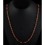 A long 18ct yellow gold coral necklace, with pierced gold links alternating with coral beads each