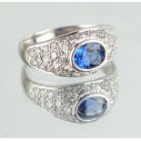 A modern 18ct white gold sapphire & diamond ring, the oval cut Ceylon sapphire weighing