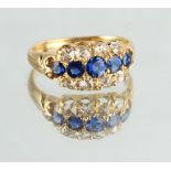 An unmarked yellow gold sapphire & diamond three row ring, with a centre row of five graduated round