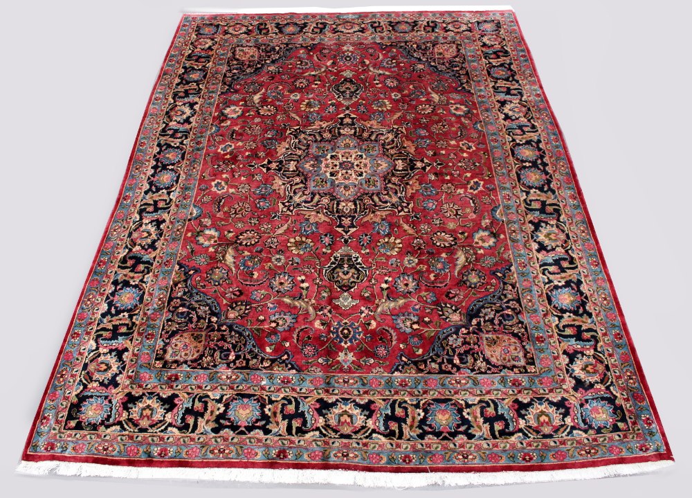 A Meshed woollen hand-made carpet with dark red ground, 134 by 97ins. (340 by 245cms.) (see