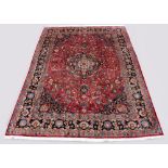 A Meshed woollen hand-made carpet with dark red ground, 134 by 97ins. (340 by 245cms.) (see