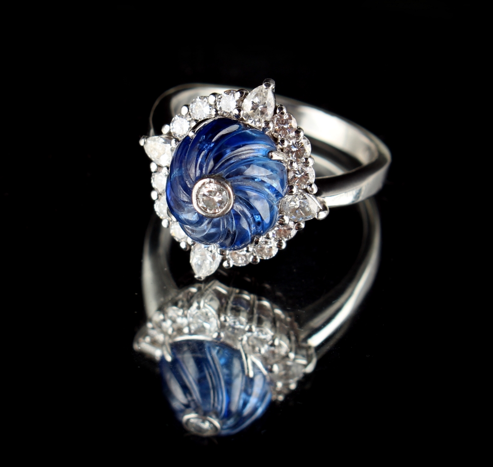 An unusual platinum sapphire & diamond cluster ring, the spiral carved cabochon sapphire weighing an