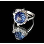 An unusual platinum sapphire & diamond cluster ring, the spiral carved cabochon sapphire weighing an