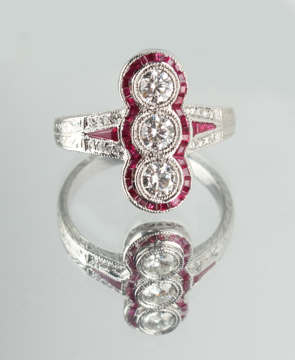 An 18ct white gold ruby & diamond ring, with three round brilliant cut diamonds set within a