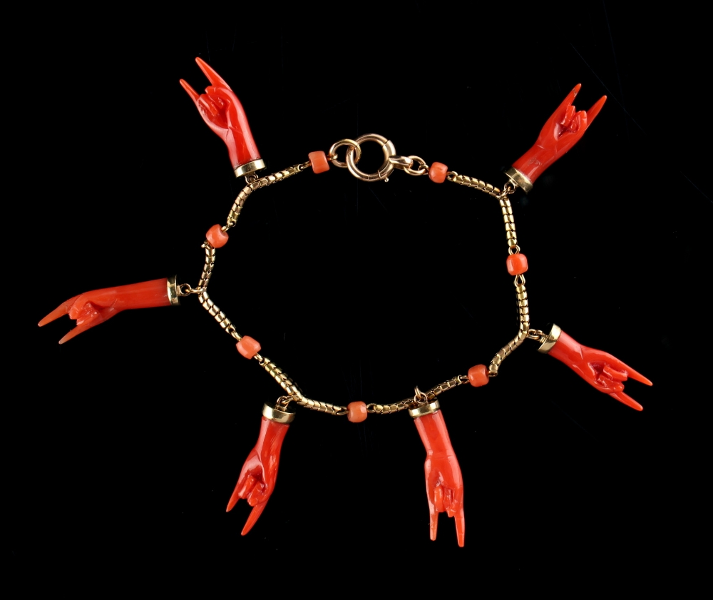 A yellow gold & coral fringe bracelet, with six pendant carved coral hands, the chain with seven