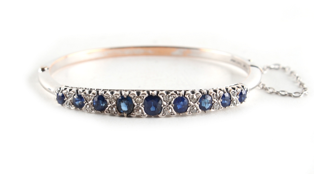 A white gold sapphire & diamond hinged bracelet, the nine oval cut sapphires weighing a total of