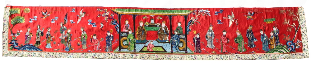 A Chinese embroidered red silk long panel depicting a court scene, late 19th / early 20th century,