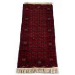 Property of a lady - an Afghan woollen hand-made long rug, with red ground, 72 by 32ins. (183 by