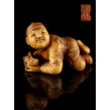The Ronald Hart Collection of Japanese Netsukes - a carved ivory netsuke modelled as a recumbent boy