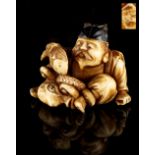 The Gill Collection of Japanese Netsukes - a carved ivory netsuke modelled as Ebisu seated with an