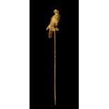 A heavy unmarked high carat yellow gold stick pin modelled as a falcon tethered to a perch, the bird