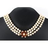 A pearl three strand necklace, the individually knotted uniform pearls approximately 8mm diameter,