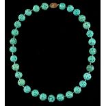 A Chinese carved turquoise bead necklace, the thirty-one uniform beads each carved with two shou