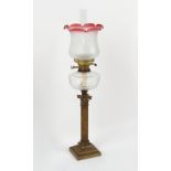 Property of a lady - a brass Corinthian column oil lamp with cranberry tinted glass shade, 30ins. (