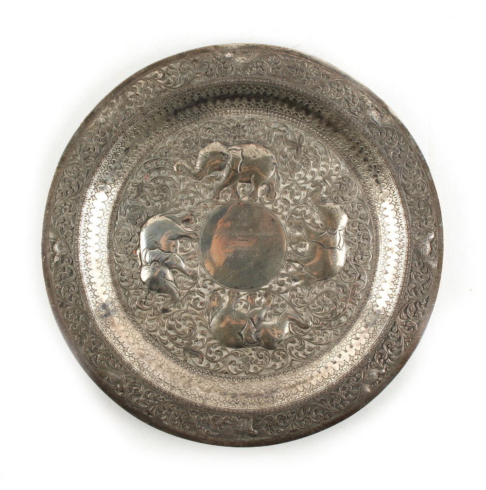 An Indian white metal (tests silver) circular plate, decorated in repousse with elephants,