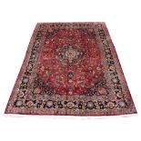 A Meshed woollen hand-made carpet with dark red ground, 134 by 97ins. (340 by 245cms.) (see