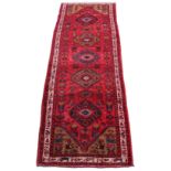 A Hamadan woollen hand-made runner with red ground, 116 by 39ins. (295 by 100cms.) (see