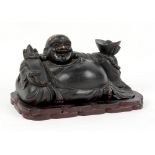 A Chinese carved & black painted wood figure of Budai, modelled recumbent & holding a ruyi