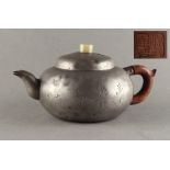 A 19th century Chinese pewter teapot with incised flowers & calligraphy, the cover with pale celadon