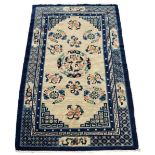 A mid 20th century Chinese wool rug, with ivory field within navy borders, 85 by 53ins. (216 by