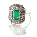 An Art Deco emerald & diamond cluster ring, the octagonal cut Colombian emerald weighing an
