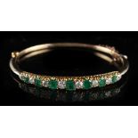 A Victorian yellow gold emerald & diamond hinged bangle, circa 1890, set with seven graduated