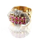 A modern heavy unmarked yellow gold ruby & diamond buckle ring, the ten round cut rubies weighing an