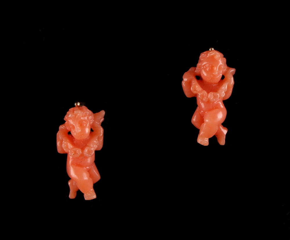 A pair of carved coral earrings, with clip & post fastenings, each with a carved coral putto holding