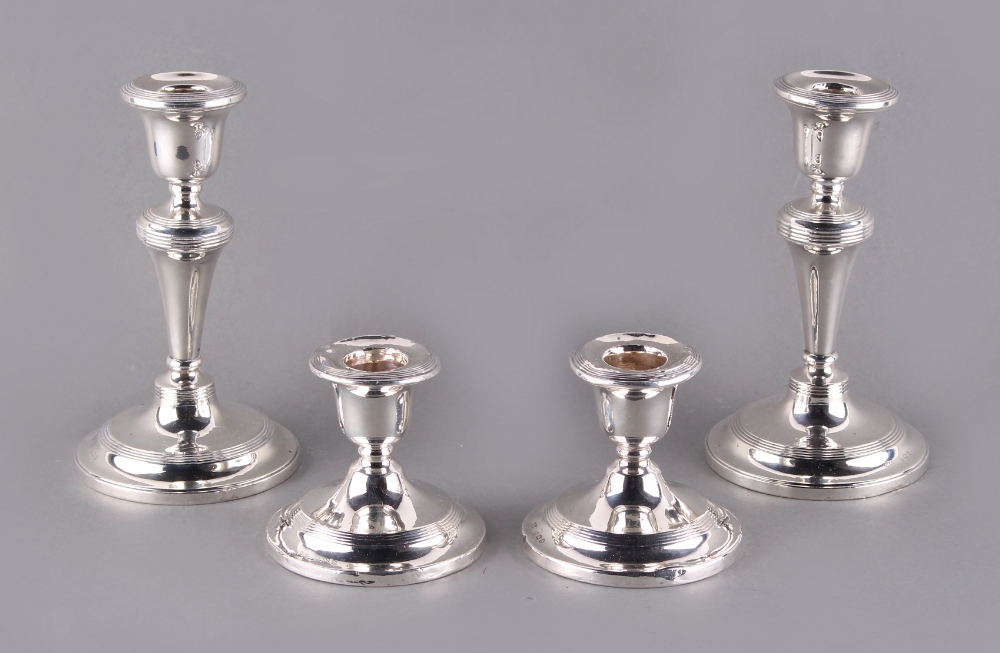 Property of a lady - two pairs of early 20th century silver candlesticks, the larger pair Birmingham