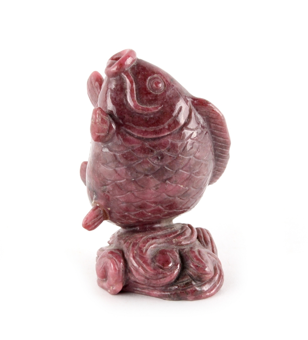 A carved pink hardstone, possibly rhodonite, model of a fish emerging from water, 3.45ins. (8.7cms.)