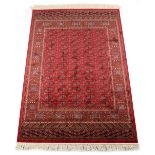 A Bokhara style rug with red ground, 75 by 53ins. (190 by 135cms.) (see illustration).