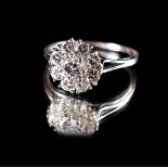 An unmarked white gold diamond flowerhead cluster ring, with central round brilliant cut diamond